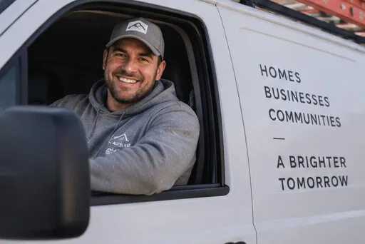 Contractor smiling from the driver's seat of a white work van
